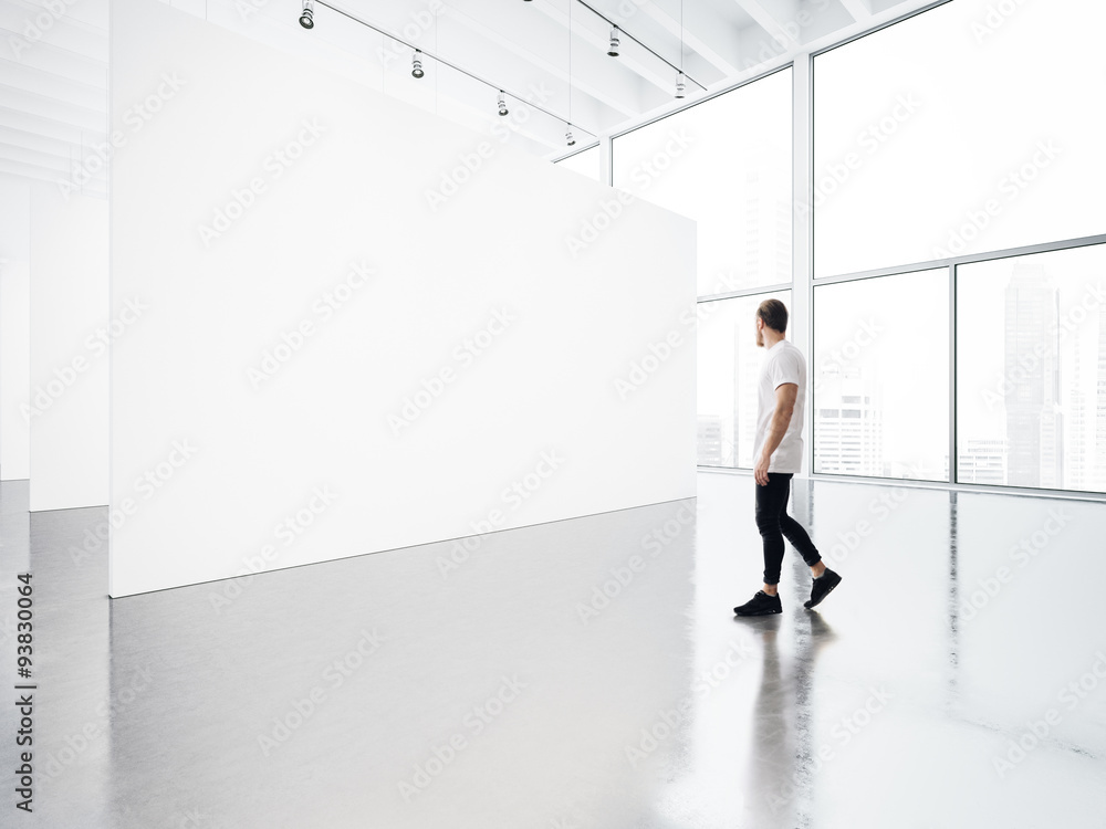 Empty gallery interior with white canvas and young man.  - obrazy, fototapety, plakaty 