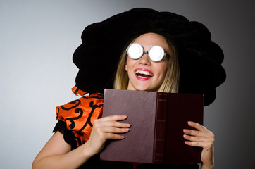 Witch with book in dark studio