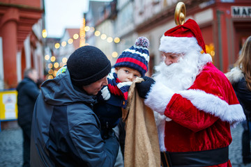 Wall Mural - Little toddler boy with father and Santa Claus on Christmas market