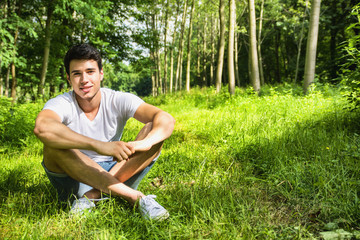 Wall Mural - Fit handsome young man relaxing lying on lawn grass