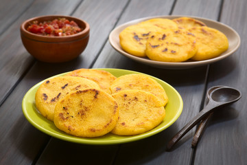 Wall Mural - Colombian arepas made of corn meal with hogao sauce (tomato and onion cooked) in the back (Selective Focus, Focus on the first arepas)