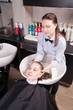 © julenochek - Hairdresser washing a woman's blond hair