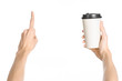 Breakfast and coffee theme: man's hand holding white empty paper coffee cup with a brown plastic cap isolated on a white background in the studio, advertising of coffee first-person view