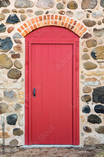 Nowoczesny obraz na płótnie Bright Red Arched Door in a Stone Wall