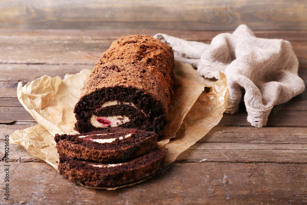 Chocolate roll with cream and berries on table close up