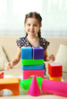 © Africa Studio - Little girl playing with cubes on home interior background