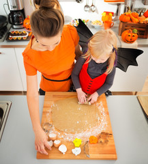 Wall Mural - Girl in bat costume with mother making Halloween biscuits