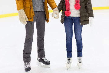 Canvas Print - close up of happy couple skating on ice rink