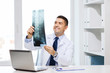© Syda Productions - smiling male doctor in white coat looking at x-ray