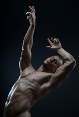 Bodybuilder and strip theme: beautiful with pumped muscles naked man posing in the studio on a dark background