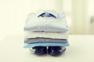 close up of folded male shirts and shoes on table