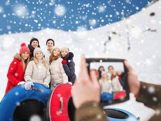 Wall Mural - smiling friends with snow tubes and tablet pc