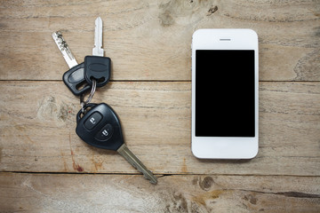 Mobile phone and car remote keys on wooden background