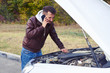 © ArtFamily - discontented man looking under the hood of breakdown car