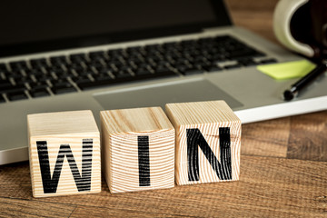 Wall Mural - win written on a wooden cube in front of a laptop