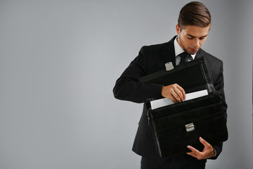 Wall Mural - Elegant man in suit with briefcase on gray background