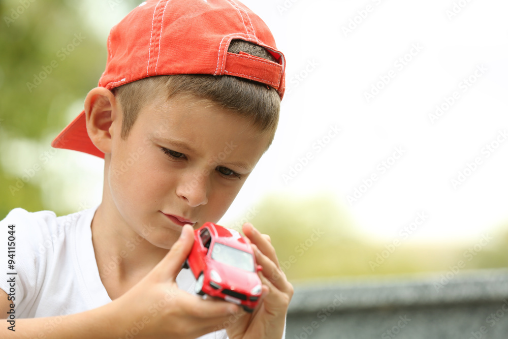 Little boy playing with toy car outside