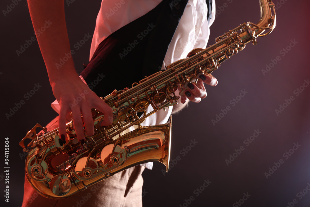 Saxophone in female hands on dark background, close up