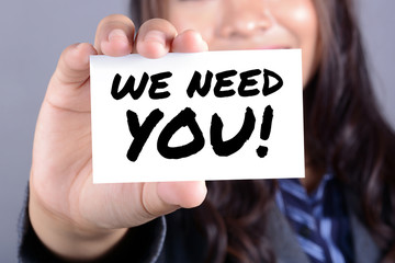 WE NEED YOU! message on the card shown by a businesswoman