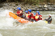 A group of friends wearing red life jackets navigating through white water rapids on a rafting adventure, laughing and having fun as a team.