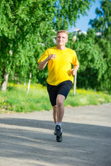 Sporty man jogging in city street park. Outdoor fitness.