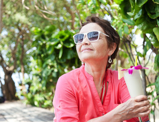 Wall Mural - beautiful elderly woman in a hat with a cocktail in hand. Summer