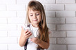 © Africa Studio - Beautiful little girl with mobile phone on light wall background