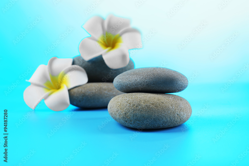 Spa stones and flowers on blue background