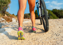 Legs Of A Woman In Sneakers With A Bicycle Close Up