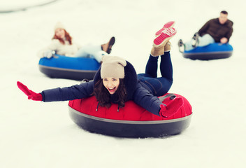 Wall Mural - group of happy friends sliding down on snow tubes