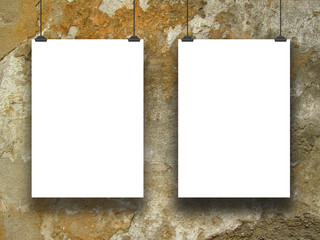 Two hanged paper sheets with clips on yellow grungy concrete wall background