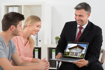 Wall Mural - Estate Agent Showing House On Laptop To Couple