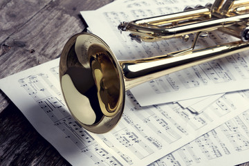 Trumpet and sheet music on old wooden table. Vintage style.