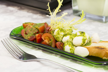 Caprese salad with tomatoes and cheese in a plate of glass