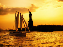 Silhouette Of The Statue Of Liberty And A Sailboat At Sunset