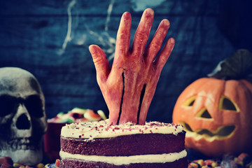 Fototapeta cake topped with a bloody hand in a scary scene for halloween