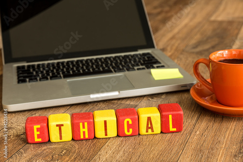 Fotografie, Obraz Ethical written on a wooden cube in front of a laptop