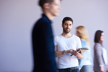 Canvas Print - student working on tablet, people group passing by