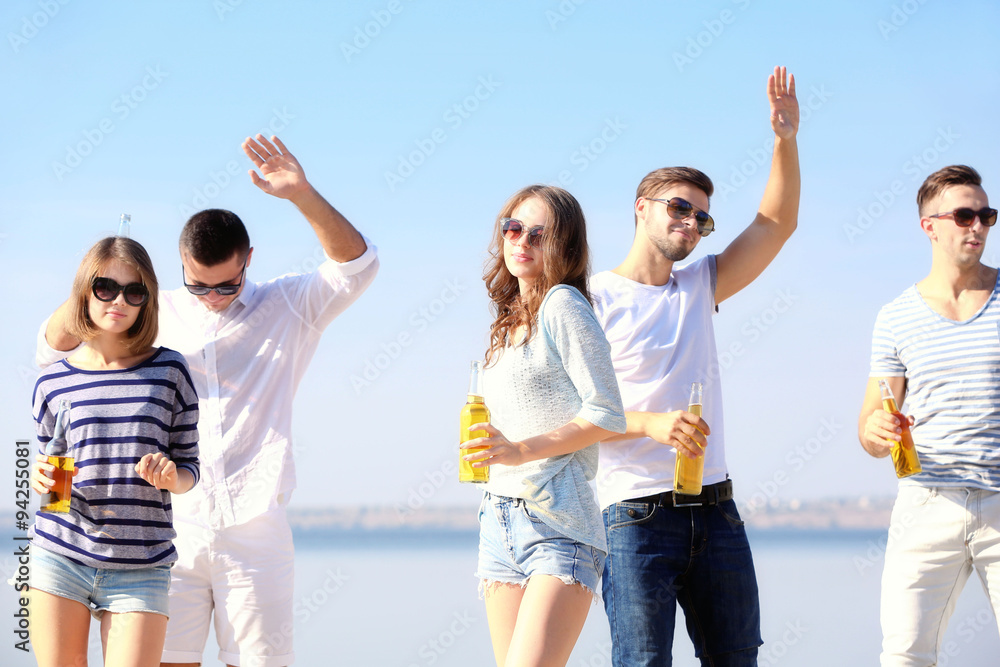 Young people with beer on the riverside