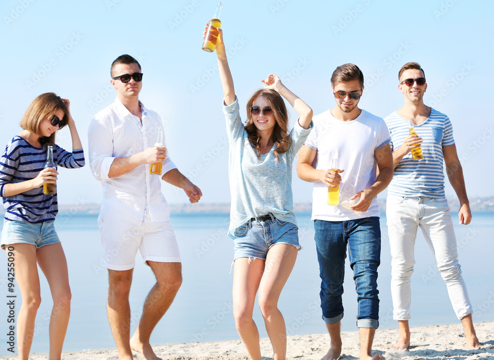 Young people with beer on the riverside
