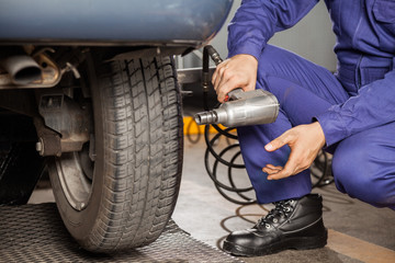 Mechanic Holding Pneumatic Wrench At Garage