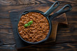 Frying pan with bolognese sauce on a rustic wooden background