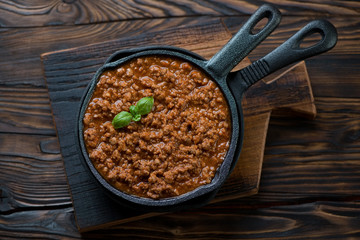 Wall Mural - Frying pan with bolognese sauce on a rustic wooden background