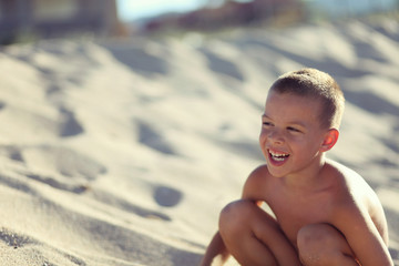 Boy alone in sand on beach with beautiful smile