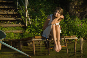 Relaxing young woman on wooden pier at the lake