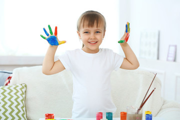 Little girl with hands in paint, on home interior background