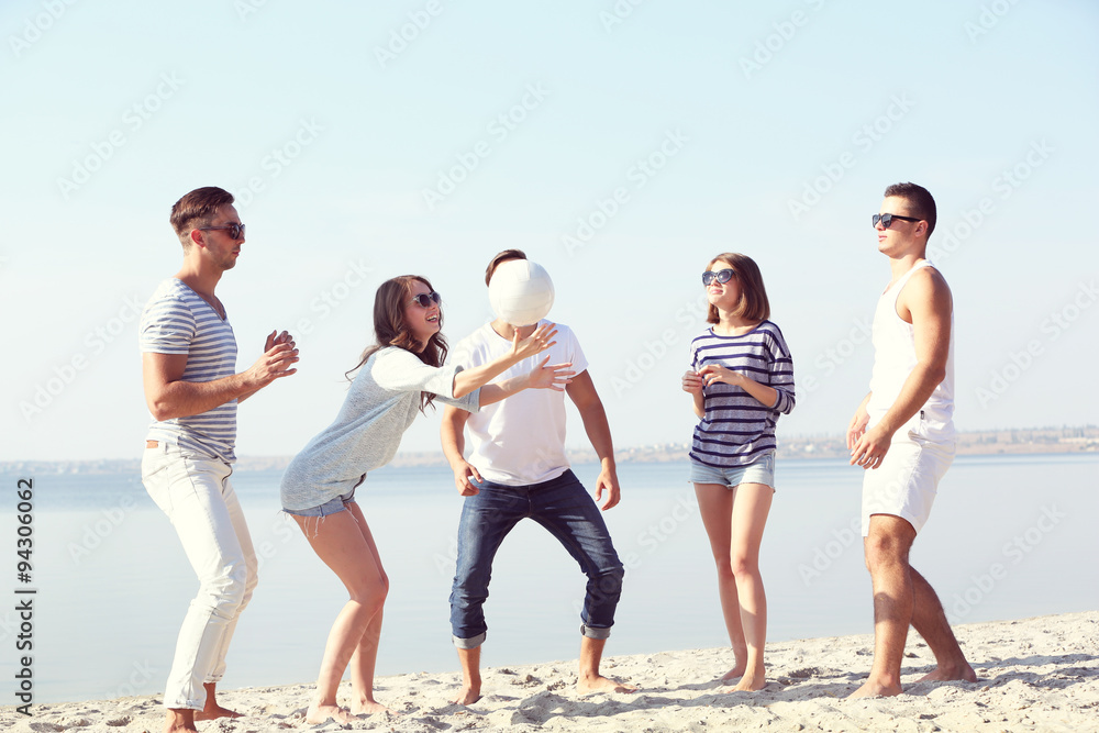 Young people playing with ball on the riverside