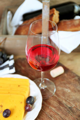 Still life of wine, grape, cheese and bread on rustic wooden background