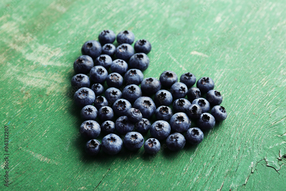 Heart shaped bilberries on old wooden background