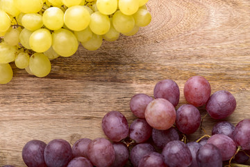 bunches of white and red grapes on wooden background